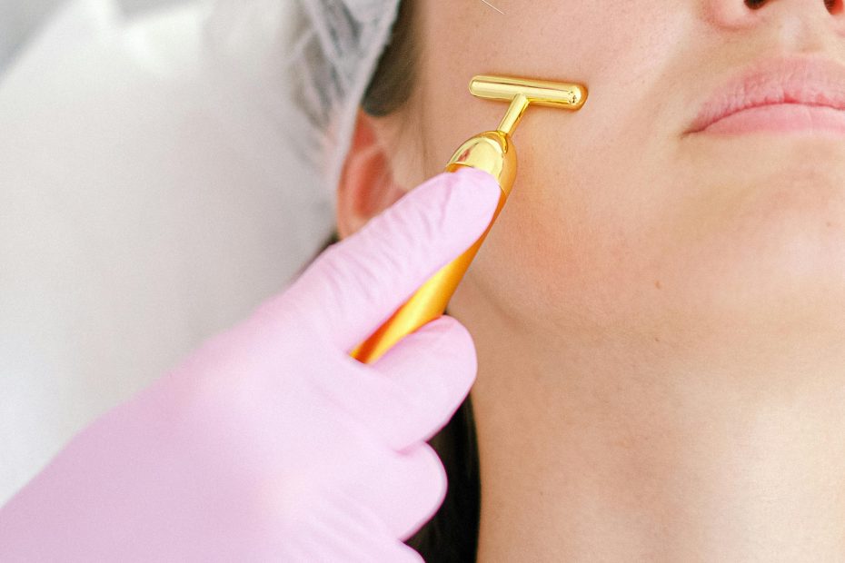 Close-up of a young woman receiving a beauty treatment involving a syringe and face roller at a clinic.